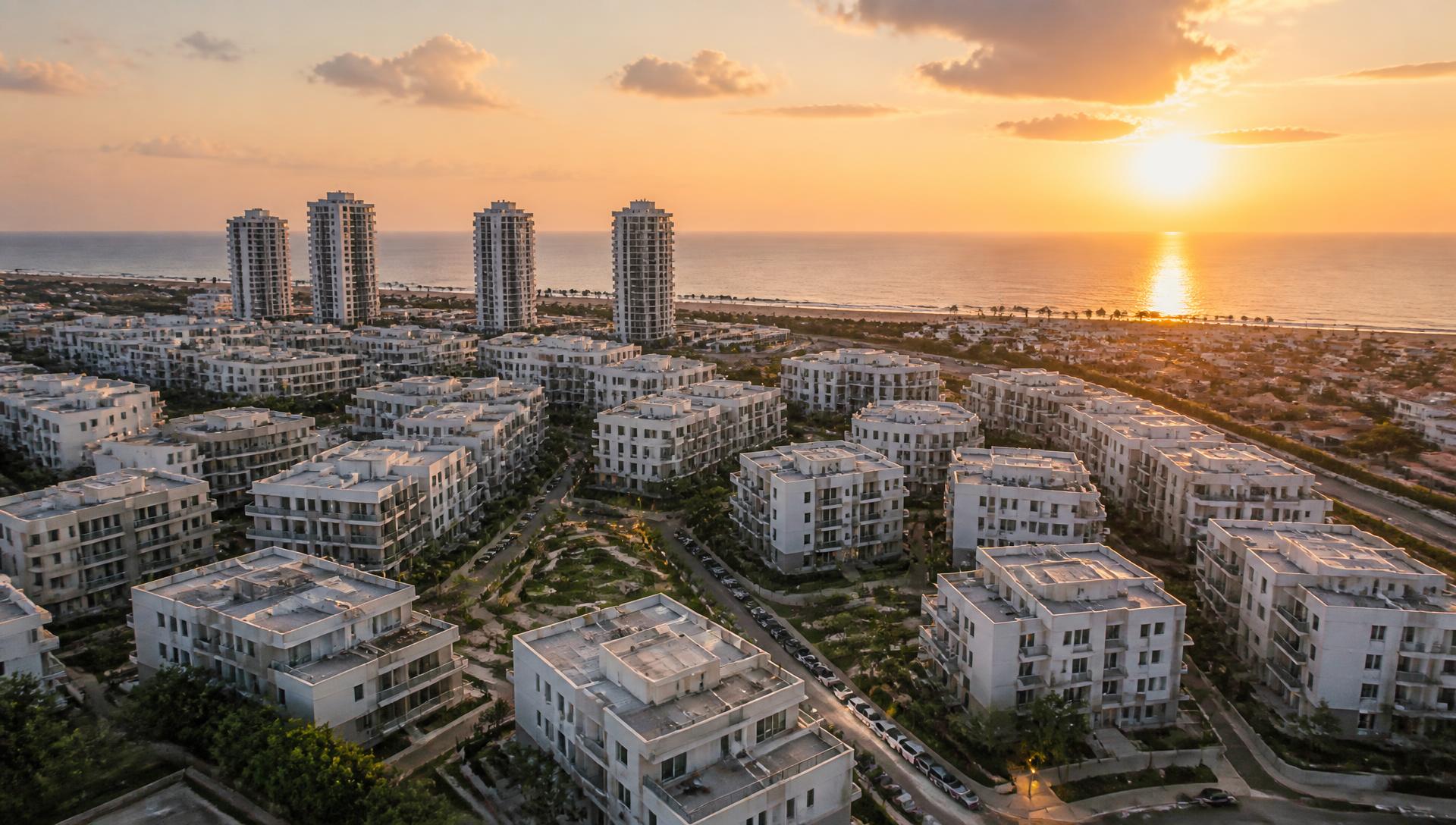 צילום אווירי בשקיעה של שכונת מגורים מודרנית מול קו החוף